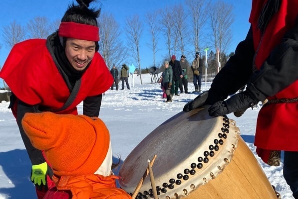 A Japanese man shows his Taiko drum to a visiting toddler