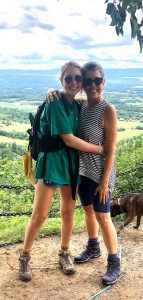 Grandmother and granddaughter on a hike- both smiling and hugging