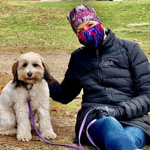 woman in a winter coat petting a dog