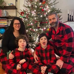 A family of four hanging out in front of a Christmas Tree in matching pajamas