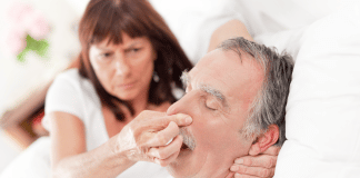 WOman plugging a sleeping man's nose