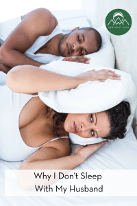 woman covering her ears in bed with a peacefully sleeping man