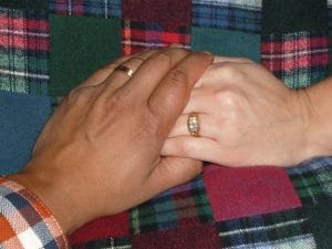 Two people holding hands showing wedding rings