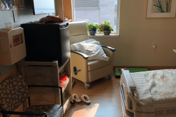 hospital room set up with plants and art and a quilt to be more homey for a long stay