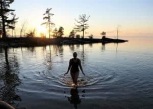 Woman walking out of lake at sunset