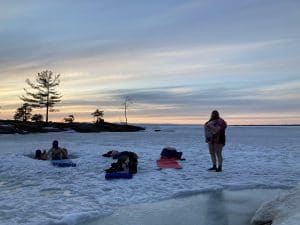 People wading in hole in icy lake water