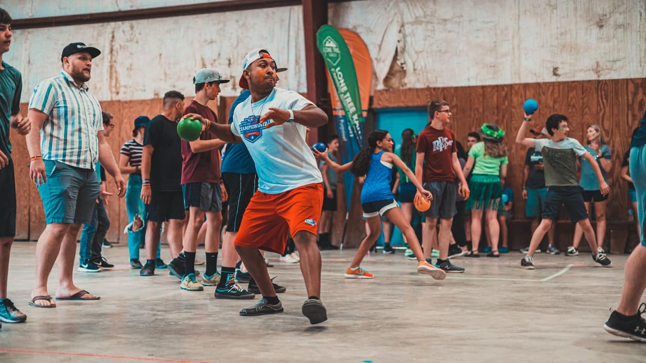 Large group of kids and adults playing dodgeball.