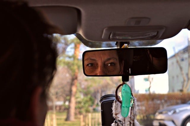 Mother looking in rearview mirror of car