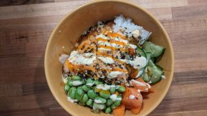 poke bowl with salmon, vegetables, and sauce