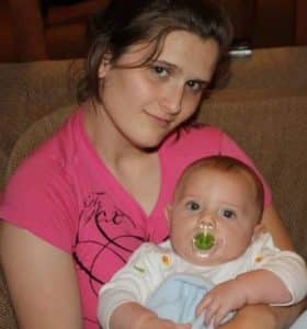 Young woman with a sad expression holding a baby