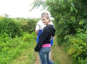 Teen girl on a green, wooded path. She looks sad and uncomfortable