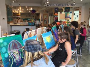 Kids of all ages painting water scenes at Burlington Paint and Sip's Paint and Create Kids Camp