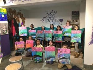 Kids holding up finished artwork at camp