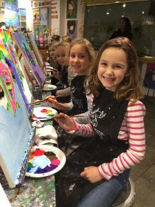 two young girls smiling and painting during the Burlington Paint and Sip Paint and Create Kids' Camp