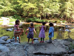 Four children playing near a swimming hole