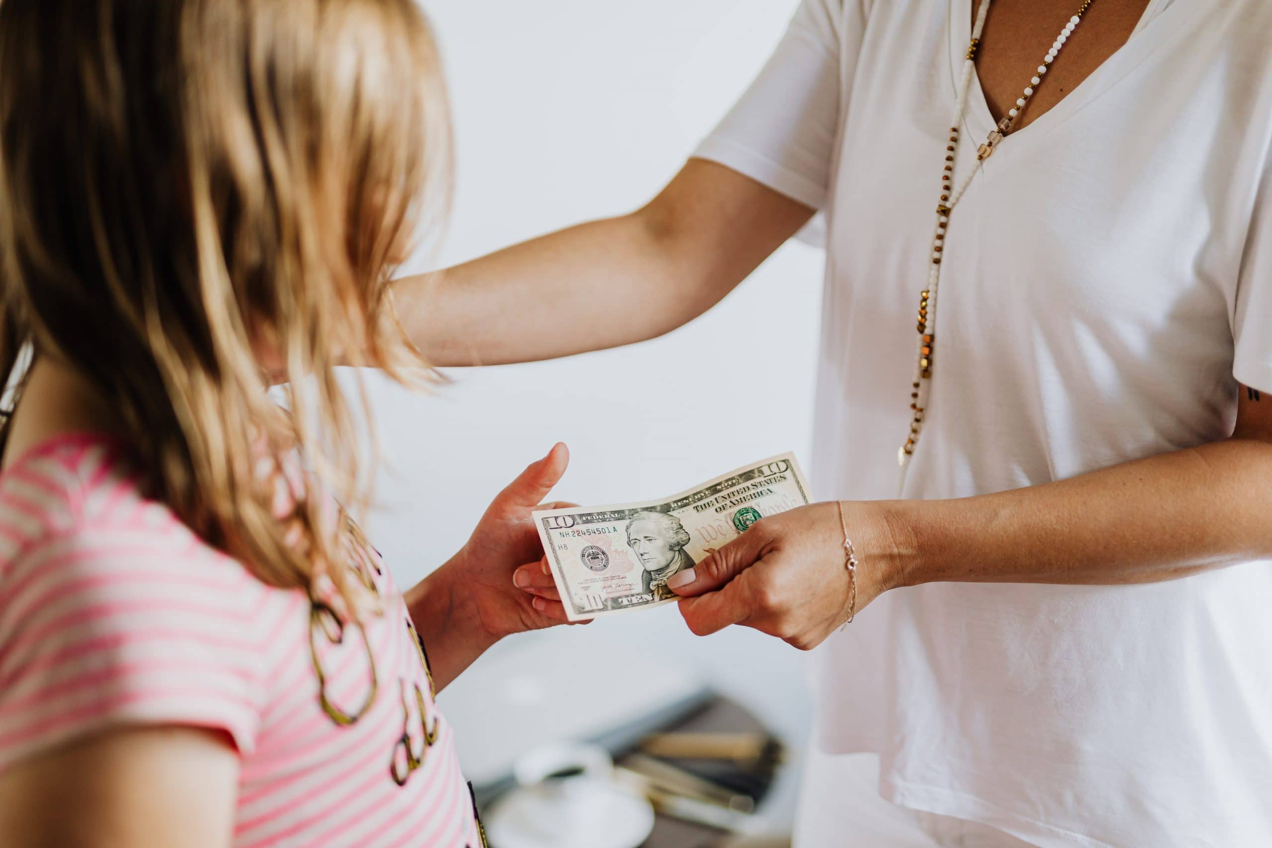 Teaching Dollars and Sense – Financial Literacy for Children Mother handing young female $10.