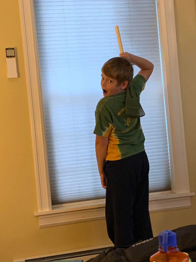 10 year old boy modeling how to use his miniature rake back scratcher.
