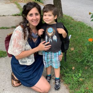 woman kneeling next to her preschool-aged son. Both are smiling.