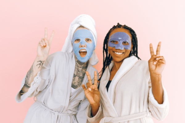 two women with beauty face masks and robes on