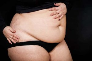 a woman in cropped top and underwear with one hand on her stomach
