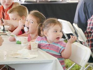 children sitting at a table and eating ice cream from plastic cups at a Vermont Breakfast on the Farm event