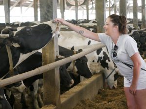woman smiling as she pats a cow's nose