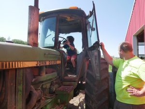 farmer standing by a tractor while a little boy pretends to drive