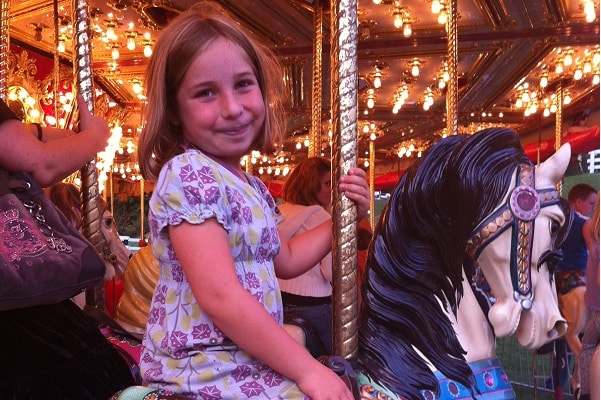 A young girl rides a horse on a fair merry-go-round.