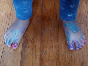 Toddler feet covered in ail polish and glitter paint