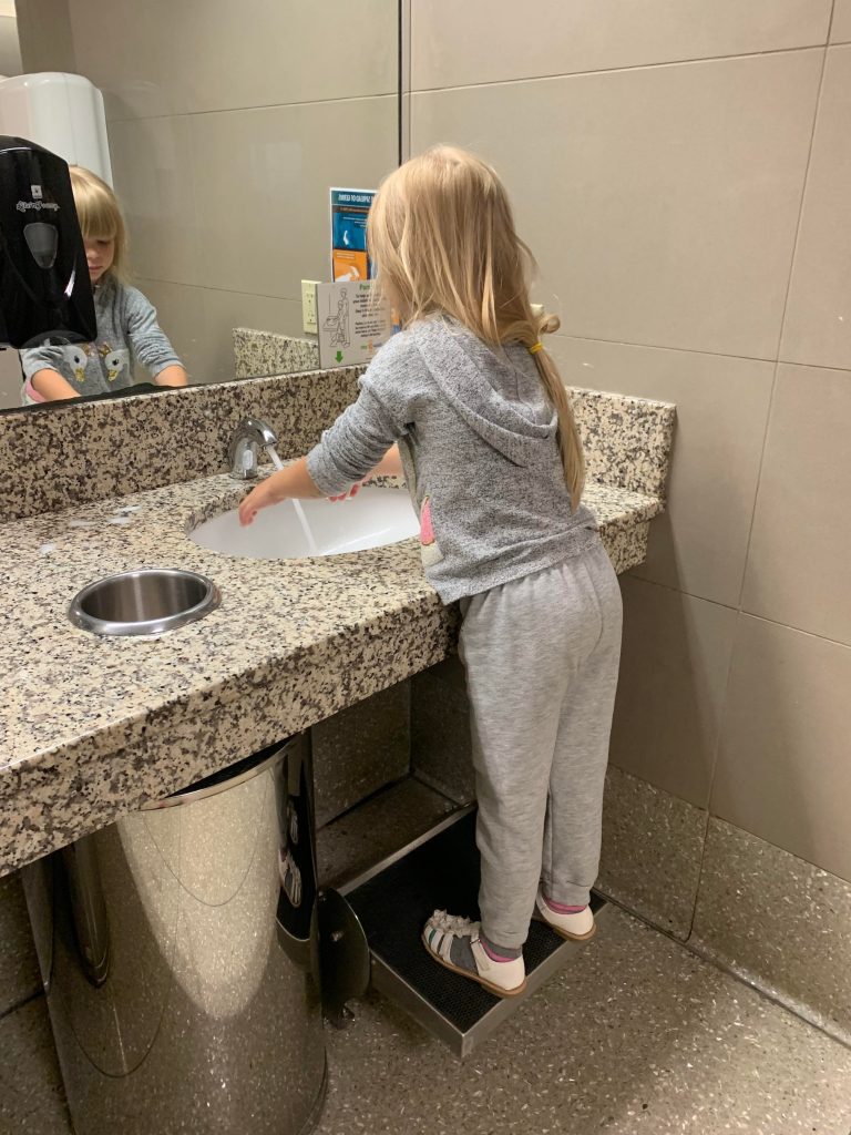 child washing hands at an airport sink