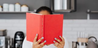 Get Your Book Club on: Great Books for Busy Moms A person holding up a book with a red cover in front of their face