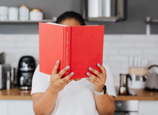 Get Your Book Club on: Great Books for Busy Moms A person holding up a book with a red cover in front of their face