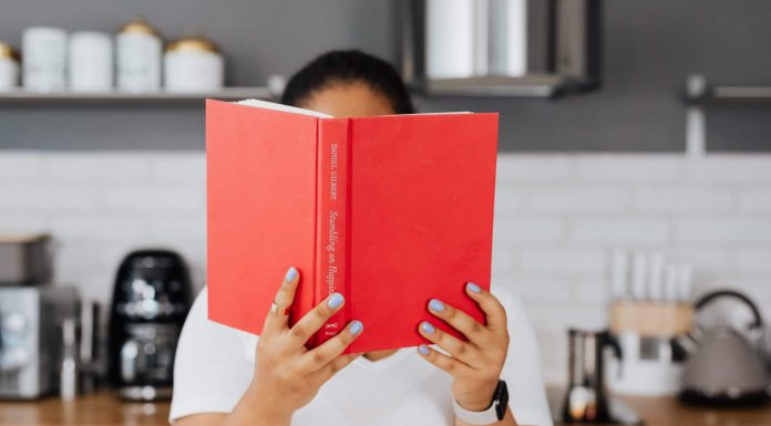 Get Your Book Club on: Great Books for Busy Moms A person holding up a book with a red cover in front of their face