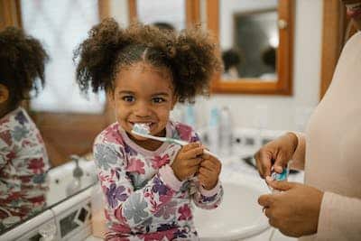 girl in pigtails brushing her teeth