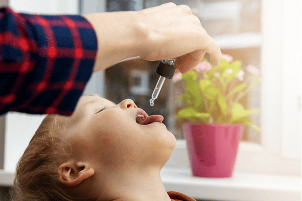 Parent giving boy vitamin supplement.