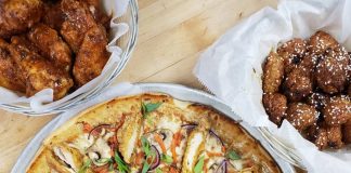 one whole pizza and two serving platters with bone-in and boneless chicken wings
