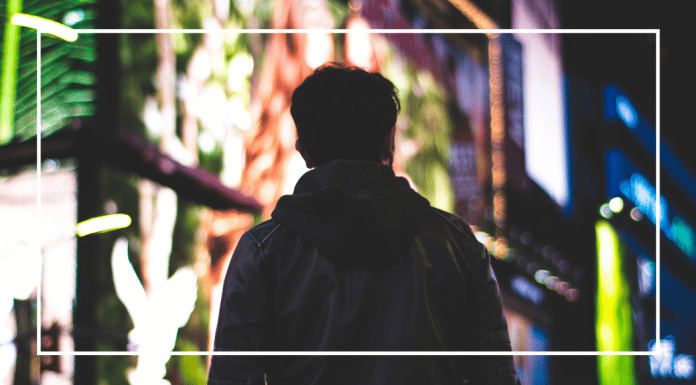 7 Things I Wish I Had Known When My Son Started Applying to College A teenage boy looks down a city sidewalk illuminated by lights.