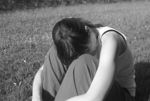person sitting with head between their knees