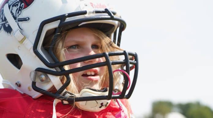 Meet the 8-Year-Old Who is Making Her Presence Known in Flag Football Young girl wearing a football helmet and a red jersey