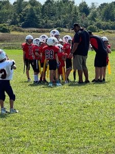 Flag football team on the field listening to their coach