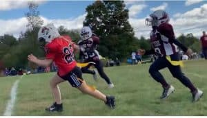 Young girl playing flag football runs with the ball. She is chased by two players from the opposing team