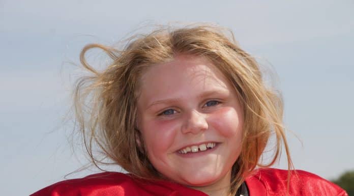 A Girl Playing Football? Meet One Who Is Dominating the Game Young girl with her hair all messed up from removing her football helmet, smiles at the camera