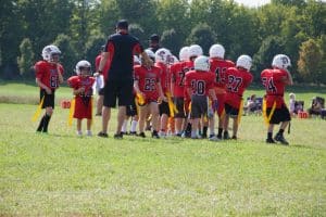Flag football team in red uniforms gathering in a huddle on the field