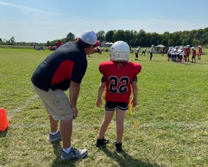 A flag football coach bends down to speak to a young female player