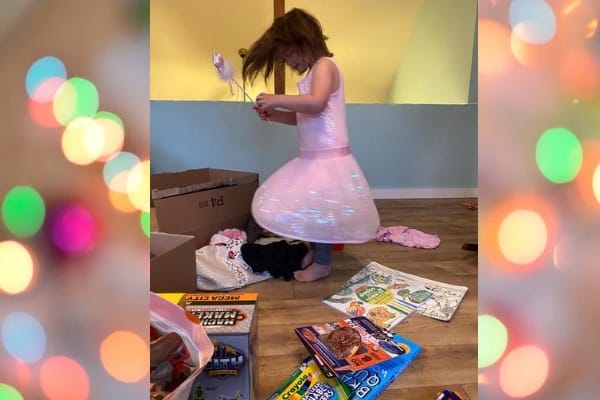 girl in a pink dress spinning and playing with a pile of toys