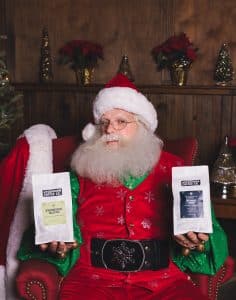 Santa holding two bags of Uncommon Coffee coffee beans