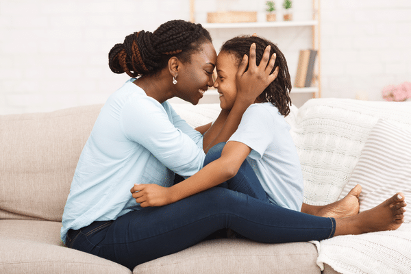 Mom hugging child while sitting on couch.