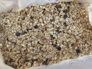 Chocolate chip granola bars spread out in pan before being cut
