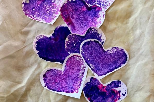 easy preschool valentine stamped hearts in a line down the middle of the picture on a cloth background