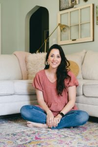 Kailee Noland, shoes for toddlers expert, sits on her living room floor.